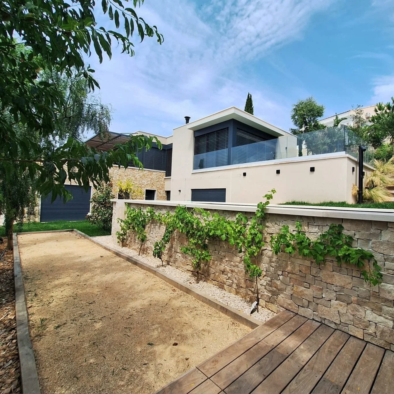 Une terrasse bois et un jardin autour d’une maison
